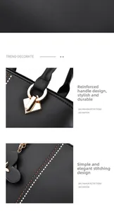 Detalle de bolso negro con asas metálicas doradas reforzadas y colgante de flor