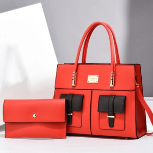 Detail of red two-piece tote bag set with black accent pockets and gold metal hardware