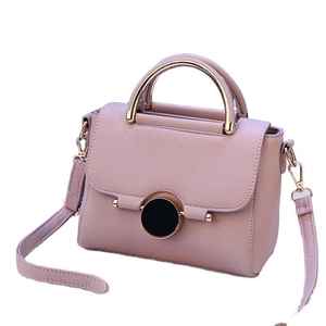 Elegant dusty pink crossbody bag with circular lock and gold metallic handle handle