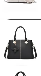 Detalle del bolso negro de cuero sintético con remaches decorativos y dije de trébol