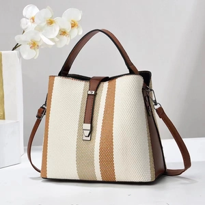 Contrast color woven texture bucket bag with brown leather handles in a side-view studio shot