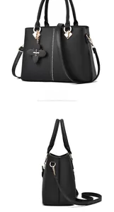 Detalle del bolso negro con colgante de trébol de cuatro hojas y herrajes dorados