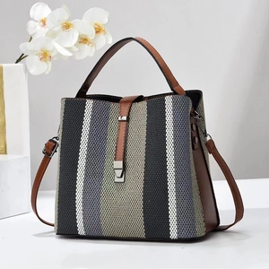 Vertical striped canvas bucket bag with brown leather handles and adjustable shoulder strap