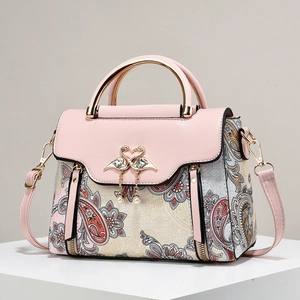 Pink leather handbag with vintage paisley patterns and golden swan clasp detail