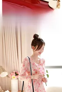 Close-up of pink floral dress with ruffle detail and black chain bag accent