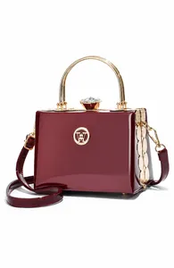 Macro detail of wine red patent leather evening bag with rhinestone lock and metal handle