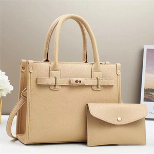 Detailed view of beige tote set featuring pebbled texture and gold twist-lock hardware
