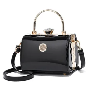 Glossy black patent leather handbag with gold handle and crystal buckle detail