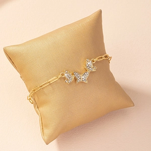 Elegant gold butterfly paperclip chain bracelet with shimmering rhinestones on satin pillow