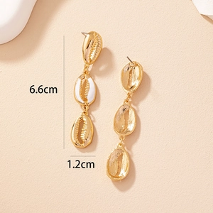 Macro detail of 6.6cm triple shell drop earrings in gold alloy and white enamel