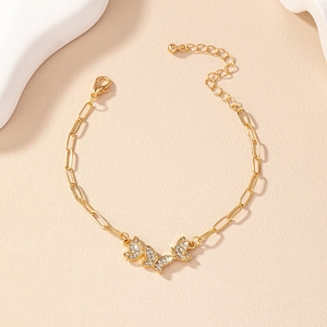 Detail of gold paperclip bracelet featuring three sparkling butterfly charms with rhinestones