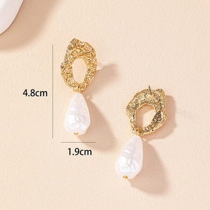 Detailed view of baroque pearl earrings with lava-textured golden hoops and drop design