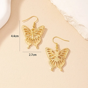 Macro shot showing dimensions of hollow butterfly gold earrings on a textured stone base