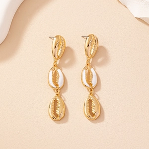 Close-up of triple-layered golden shell earrings with white enamel coating details