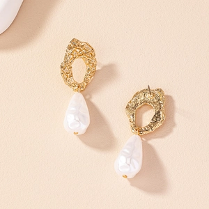 Close-up of golden baroque earrings with textured metal and white pearl teardrops