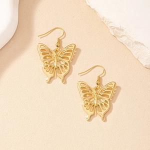 Elegant gold hollow butterfly drop earrings with delicate cutout design on beige background