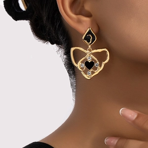 Boucles d'oreilles cœur vintage en or avec émail noir et strass sur un modèle