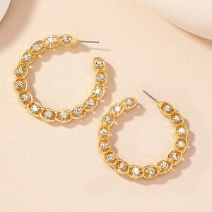 Gros plan de boucles d'oreilles créoles C dorées avec maillons creux et zircons blancs
