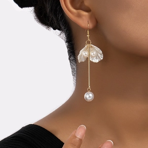 Boucles d'oreilles pendantes dorées avec pétales de nacre et perles sur un mannequin