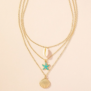 Close-up of triple-layered necklace with gold starfish, seashell, and shell charms