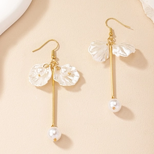 Détail de boucles d'oreilles dorées avec pétales de nacre blanche et perles pendantes
