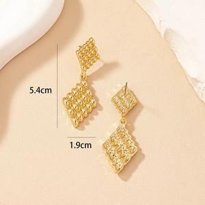 Detail shot of golden geometric diamond earrings with textured surface and 5.4cm size