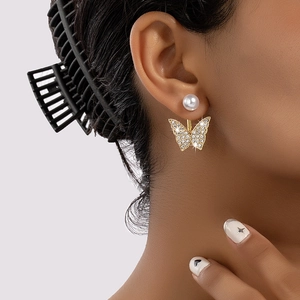 Boucles d'oreilles papillon dorées avec perles et cristaux portées par un mannequin