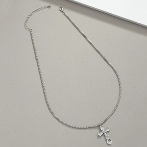 Dettaglio del ciondolo a croce d'argento vintage con motivi in rilievo e chiusura a moschettone