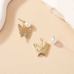 Détail de boucles d'oreilles papillon dorées avec zircons et perles blanches