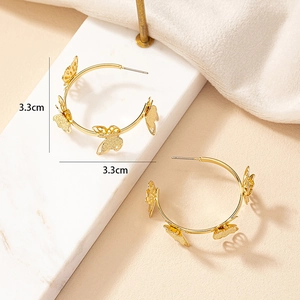 Détail de créoles papillon dorées montrant la taille de 3,3 cm et la texture de l'or mat