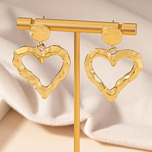 Exaggerated gold heart-shaped earrings with hammered metal texture on T-stand display