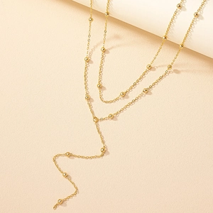 Elegant gold double-layered Y-necklace featuring small metal beads on a textured surface