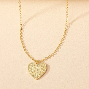 Détail du collier pendentif cœur doré avec gravure Te Amo et texture florale en relief