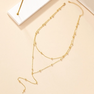 Elegant gold layered Y-necklace with metallic beads and long tassel on beige background