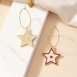 Detailed macro view of gold star dangle earrings with red enamel and textured metal