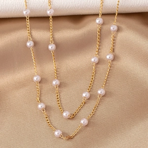 Macro shot of gold necklace with freshwater pearls on elegant champagne satin fabric