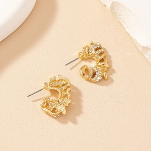 Macro detail of gold C-shaped earrings with sparkling cubic zirconia and hammered texture
