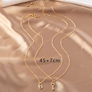 Détail du collier doré avec pendentifs serrure coeur et clé ornés de strass blancs