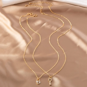 Parure de colliers dorés avec pendentifs cadenas cœur et clé sur tissu de soie chic