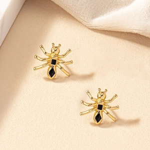 Élégantes boucles d'oreilles araignée dorées avec pierres noires sur fond doux