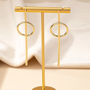 Minimalist gold geometric circle drop earrings displayed on a vertical T-bar jewelry stand