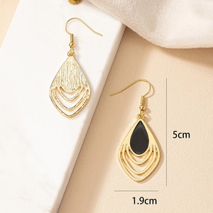 Detail of drop-shaped earrings with black enamel front and brushed gold finish on the back