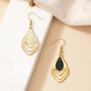Detail of vintage gold teardrop earrings with black inlay and multi-layered hollow frame