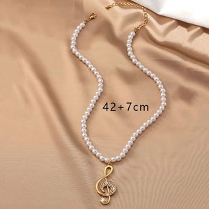 Detail of music note pearl necklace showing 42+7cm length on champagne silk background