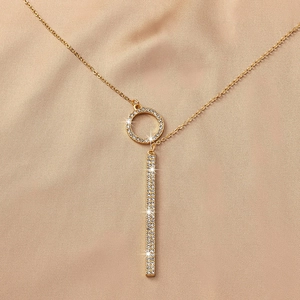 Détail du collier cercle doré avec pendentif barre en diamants pavés sur fond satiné