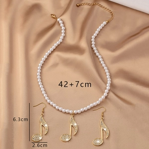 Détail de la parure de bijoux notes de musique avec strass et perles blanches sur soie