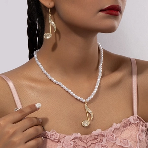 Parure de bijoux note de musique avec perles et strass portés par un mannequin femme