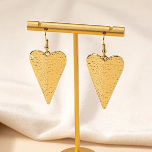 Elegant gold heart drop earrings with hammered texture on a luxury jewelry display stand