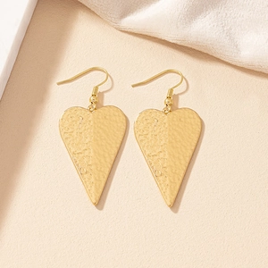 Elegant gold heart earrings with unique hammered metal texture on textured background