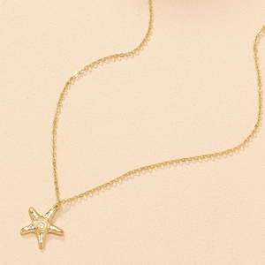 Gros plan détaillé d'un collier pendentif étoile de mer doré avec motif marin texturé